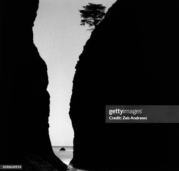 the ocean seen through a crevice in shadowed cliff - cliff gap stock pictures, royalty-free photos & images