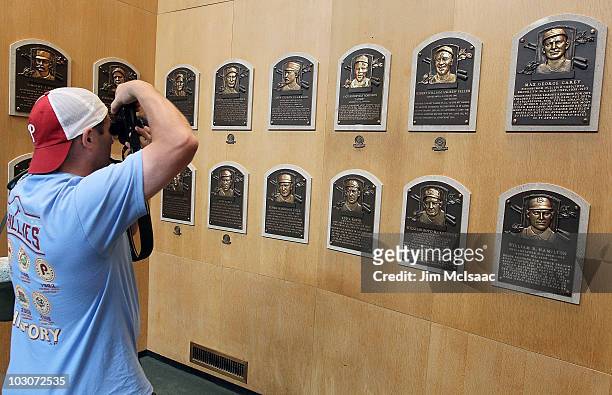 Patron of the Baseball Hall of Fame and Museum takes a photograph of the plaques of inducted members during induction weekend on July 24, 2010 in...