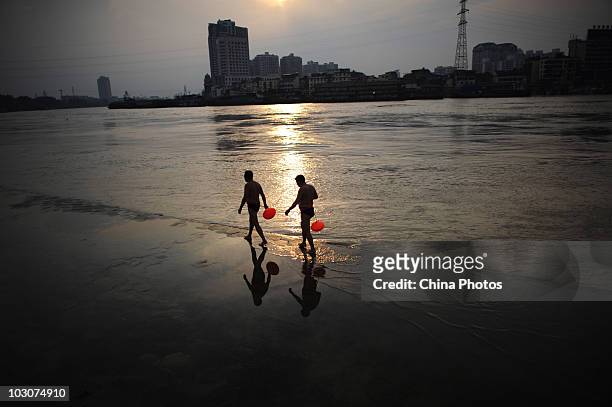Residents walk at the flooded river bank of Longwangmiao water area where the Hanjiang River merges into the Yangtze River on July 24, 2010 in Wuhan...