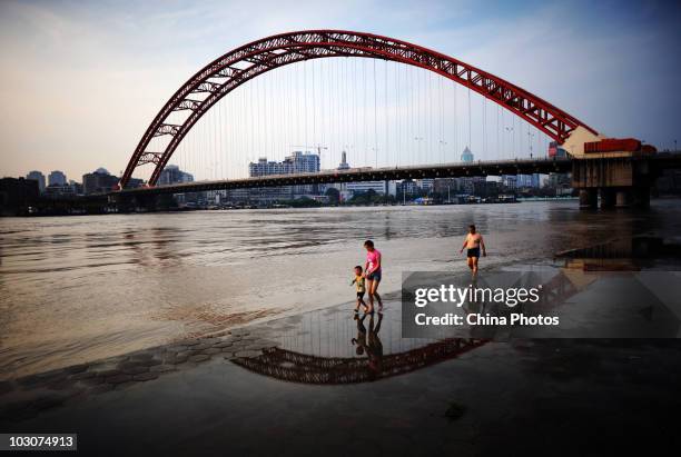 Residents walk at the flooded river bank of Longwangmiao water area where the Hanjiang River merges into the Yangtze River on July 24, 2010 in Wuhan...