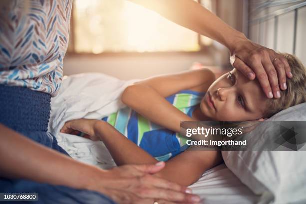 control de fiebre en la frente de niño enfermo la madre - medicina para los resfriados fotografías e imágenes de stock