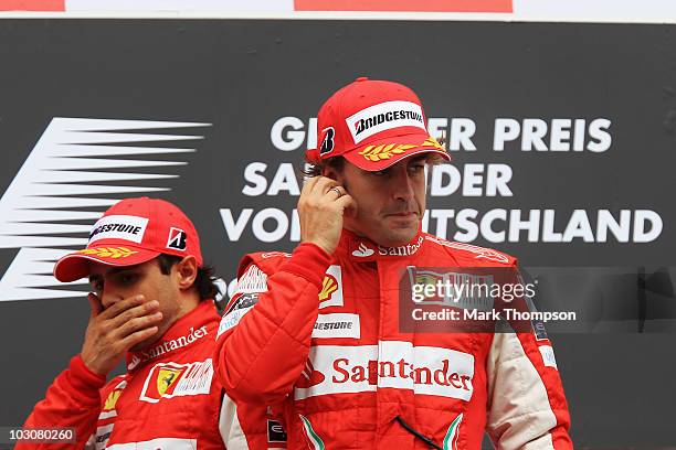 Race winner Fernando Alonso of Spain and Ferrari celebrates on the podium with second placed Felipe Massa of Brazil and Ferrari following the German...