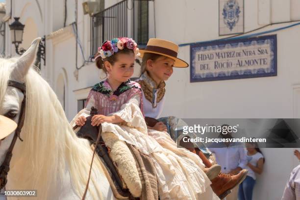 two children riding horseback during the romeria (pilgrimage) del rocio in el rocio, spain. - all horse riding imagens e fotografias de stock