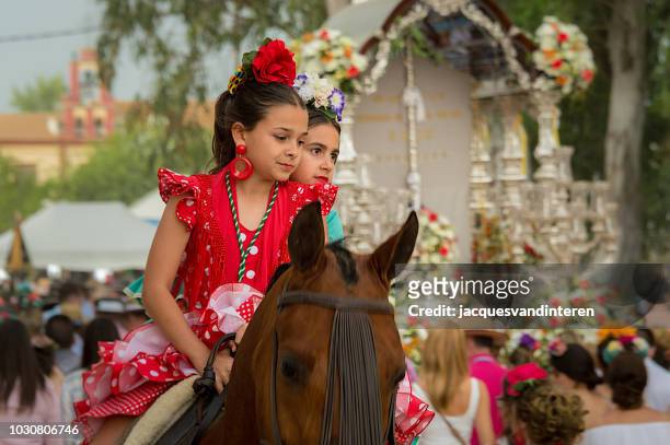 two young girls riding horseback during the romeria (pilgrimage) del rocio in el rocio, spain. - el rocio stock pictures, royalty-free photos & images