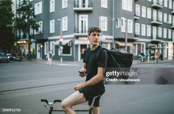 male bike courier checking his phone. - bike messenger stock pictures, royalty-free photos & images