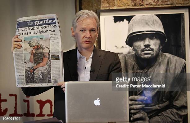 Julian Assange of the WikiLeaks website holds up a copy of The Guardian newspaper as he speaks to reporters in front of a Don McCullin Vietnam war...