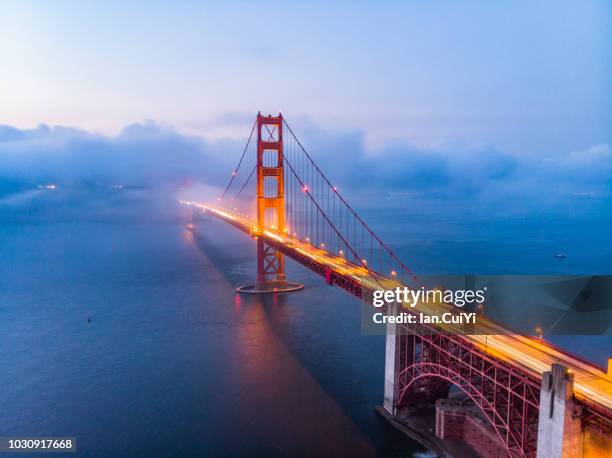 red golden gate bridge under a foggy sky (dusk) - grand lit stock pictures, royalty-free photos & images