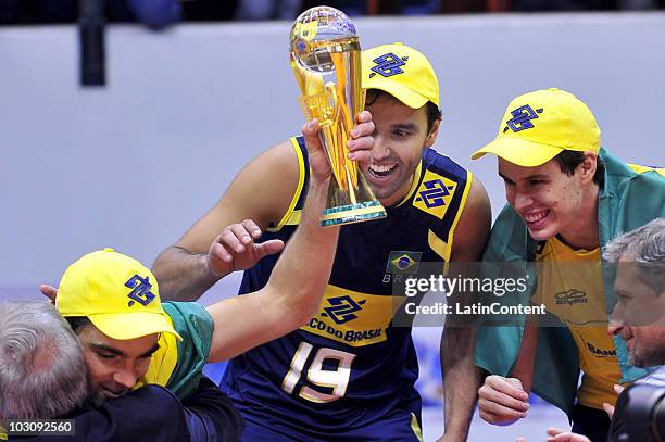 Gilberto Filho, aka Giba, with the trophy around team mates Mario Jr and Bruno Mossa during their celebration after winning the 2010 FIVB World...