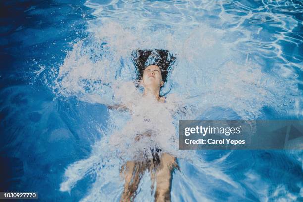 young woman splashing into a pool - jumping into water stock pictures, royalty-free photos & images