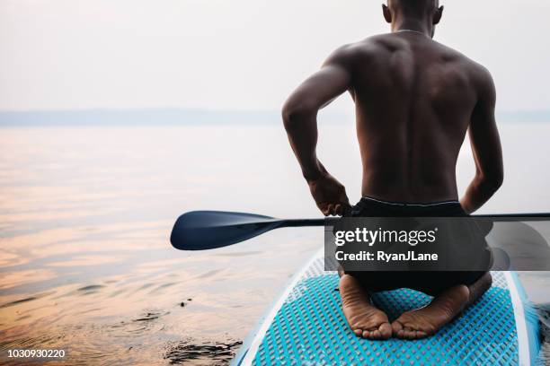 young adult man paddleboarding puget sound in summer - black people in bathing suits stock pictures, royalty-free photos & images