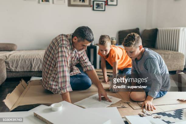 single father is assembling furniture with his kids - furniture instructions stock pictures, royalty-free photos & images