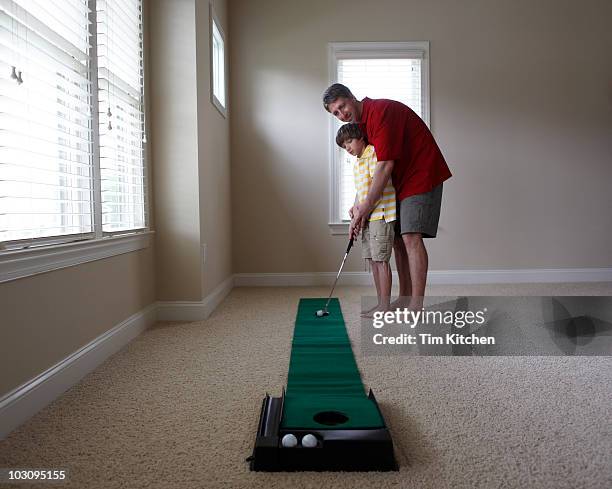 father and son practice golf in home together - indoor golf stock pictures, royalty-free photos & images