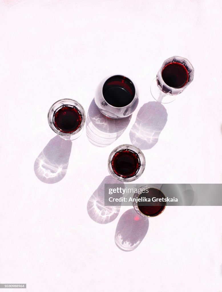 Glasses of red wine on pink background, top view