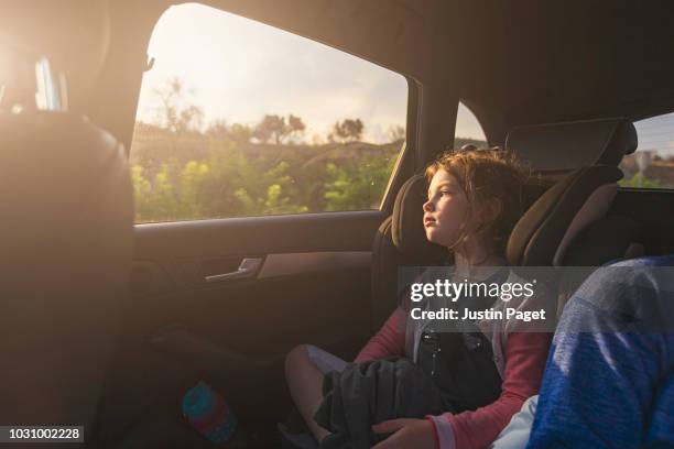young girl looking out of car window - rücksitz stock-fotos und bilder