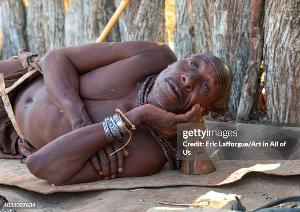 Himba tribe old man resting with his wooden pillow, Cunene Province, Oncocua, Angola on July 13, 2018 in Oncocua, Angola.