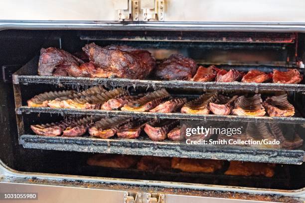 Various meats smoking in a barbecue smoker at Lucille's barbecue restaurant in Dublin, California, August 30, 2018.