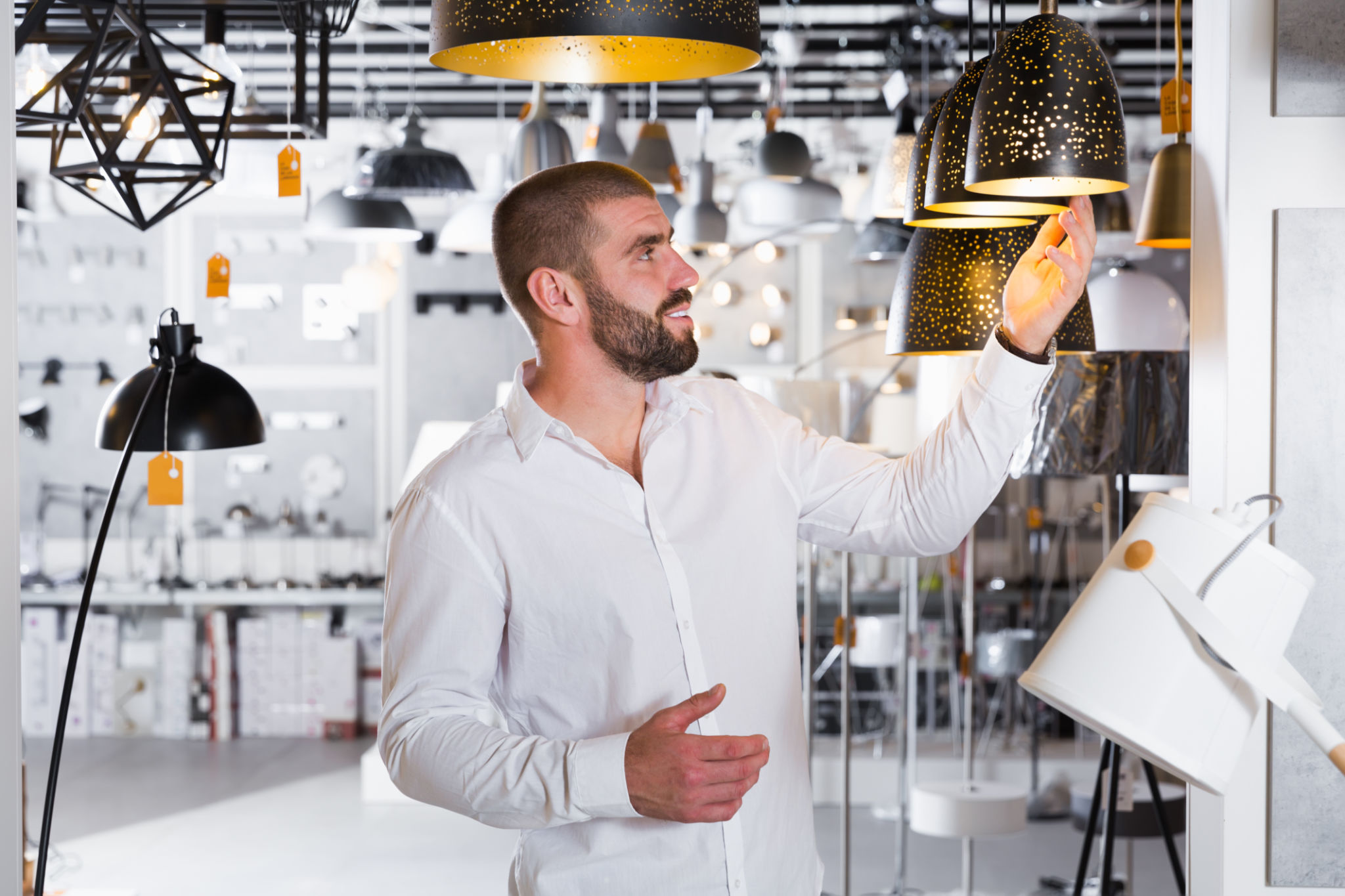 Man choosing pendent lamp in furniture showroom Man choosing pendent lamp in furniture showroom