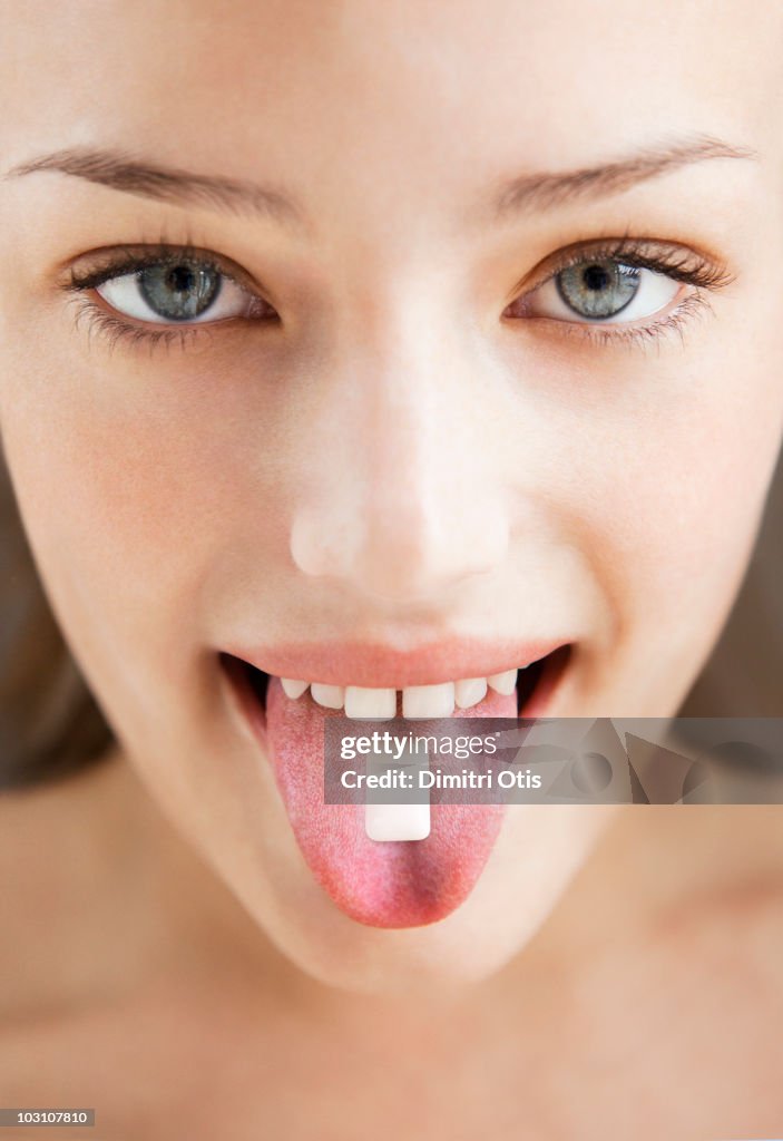 Young woman with chewing gum on her tongue