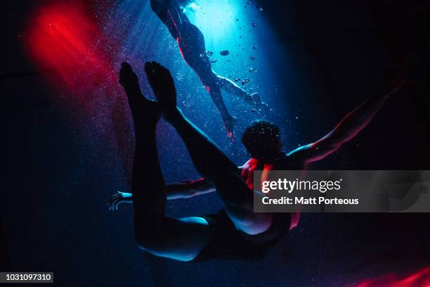 man and woman swimming in pool - woman diving underwater stock-fotos und bilder