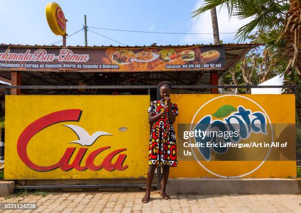 Angolan girl standing in front advertisement billboards, Benguela Province, Catumbela, Angola on July 8, 2018 in Catumbela, Angola.