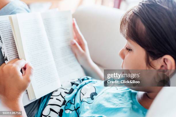 nine years old kid reading a book indoors (home interior) - 8 9 years stock pictures, royalty-free photos & images