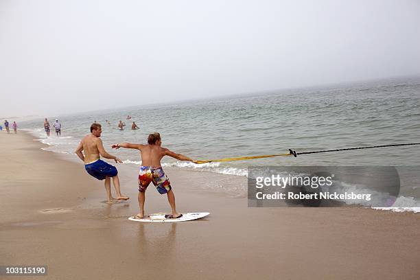 Young boys wait for a good wave July 24, 2010 to bungee skimboard the surf in East Orleans, Massachusetts. The skimboard is used to glide across the...