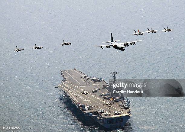 In this handout from the U.S. Navy, a U.S. Marine Corps C-130 Hercules aircraft leads a formation of F/A-18C Hornet strike fighters and A/V-8B...