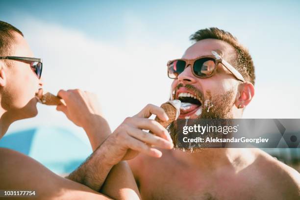 cute gay couple eating ice cream and having fun together - messy boyfriend stock pictures, royalty-free photos & images