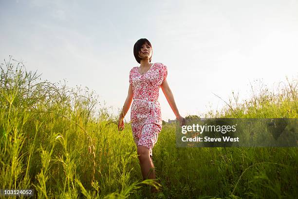 woman holding wild flowers and walking in meadow - west asia stock-fotos und bilder