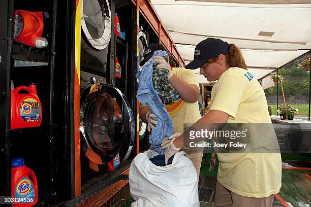 Members of the Tide's Loads Of Hope mobile laundry crew load a washing machine at the Tide's Loads Of Hope mobile laundry program at the Loads of...