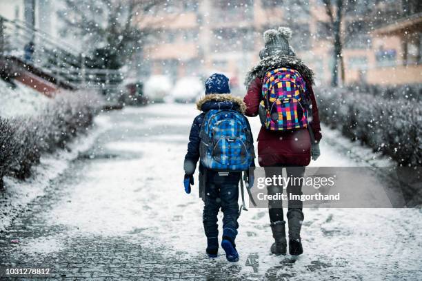 hermano y hermana van a la escuela en día de invierno - snowing fotografías e imágenes de stock