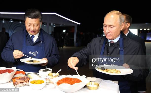 China's President Xi Jinping and Russia's President Vladimir Putin eating bliny [Russian pancakes] as he visits the Far East Street exhibition on the...