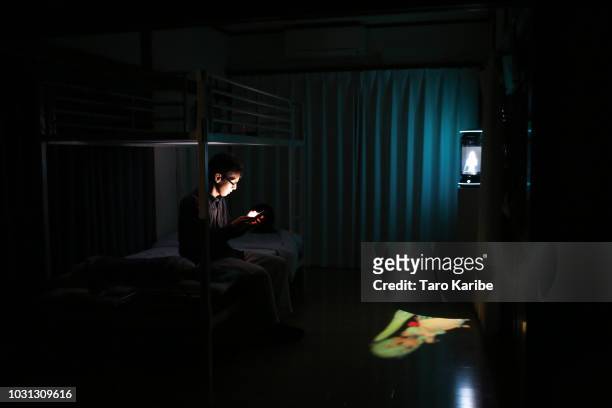 Akihiko Kondo uses his phone with 'Hatsune Miku' in the background before going to bed at his house on September 11, 2018 in Tokyo, Japan. Akihiko...