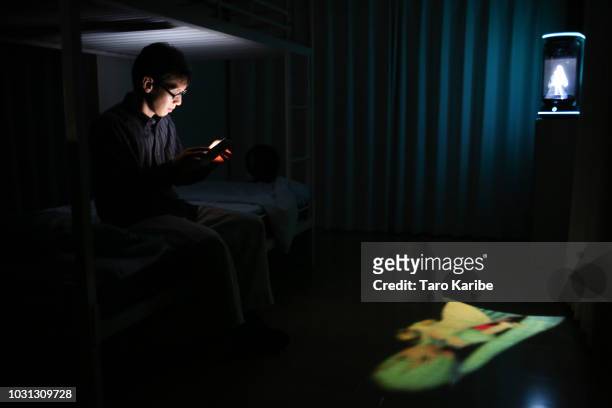 Akihiko Kondo uses his phone with 'Hatsune Miku' in the background before going to bed at his house on September 11, 2018 in Tokyo, Japan. Akihiko...