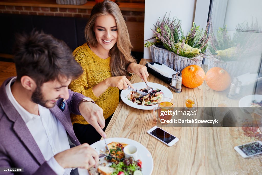 A cheerful young couple out for breakfast in a cafe before work