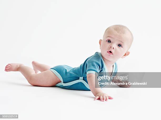 baby in blue onesie on white - allongé sur le devant photos et images de collection