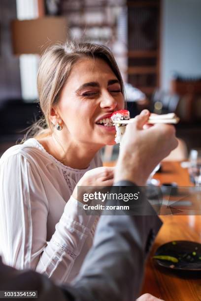 frau zum anbeißen sushi roll - eating sushi stock-fotos und bilder