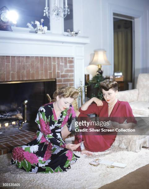 Actress Olivia de Havilland plays cards with her sister, actress Joan Fontaine, circa 1945.