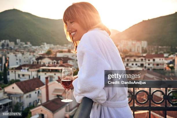 beautiful young woman enjoying on the balcony having a glass of wine - women of penthouse stock pictures, royalty-free photos & images