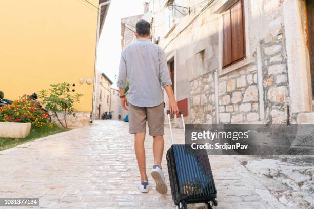 male traveller coming home - hand luggage stock pictures, royalty-free photos & images
