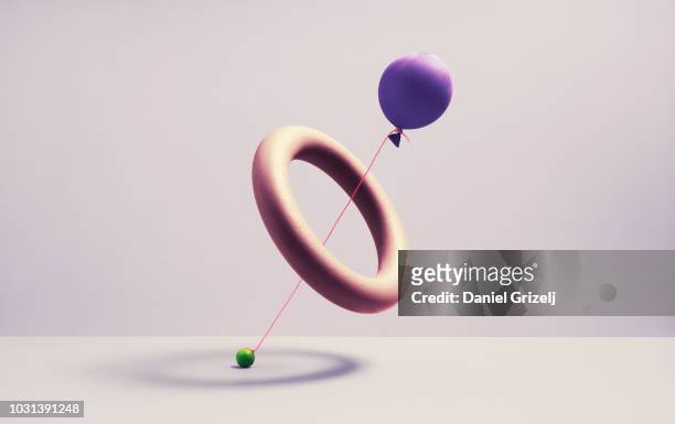 A ballon trying to drag a marble threw a spherical ring