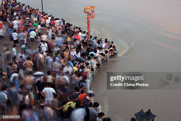 Residents watch the flood peak at the flooded river bank of Longwangmiao water area where the Yangtze River and Hanjiang River converge, on July 28,...