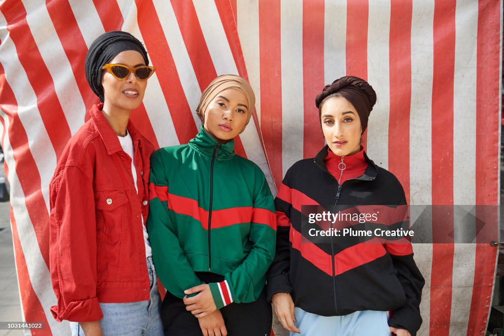 Portrait of three cool muslim women against striped background
