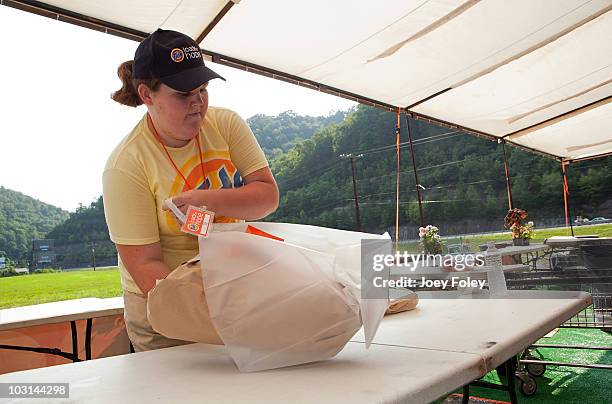 Tide crew member folds and pack clothes for residents that have dropped off their laundry at the Tide Loads Of Hope free laundry services from the...