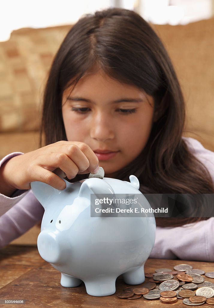 Girl feeding piggy bank #3