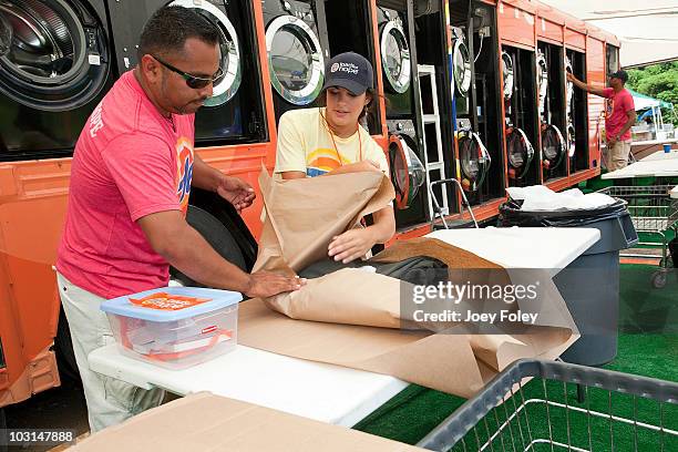 Tide crew members fold and pack clothes for residents that have dropped off their laundry at the Tide Loads Of Hope free mobile laundry services for...