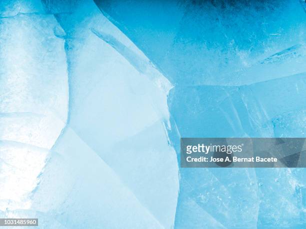 full frame of the textures formed of a block of cracked ice, on a light blue background. - ice stockfoto's en -beelden
