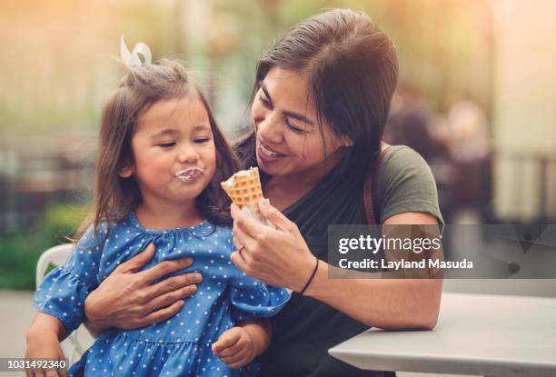 mom with child eating ice cream cone - filipino family eating stock-fotos und bilder