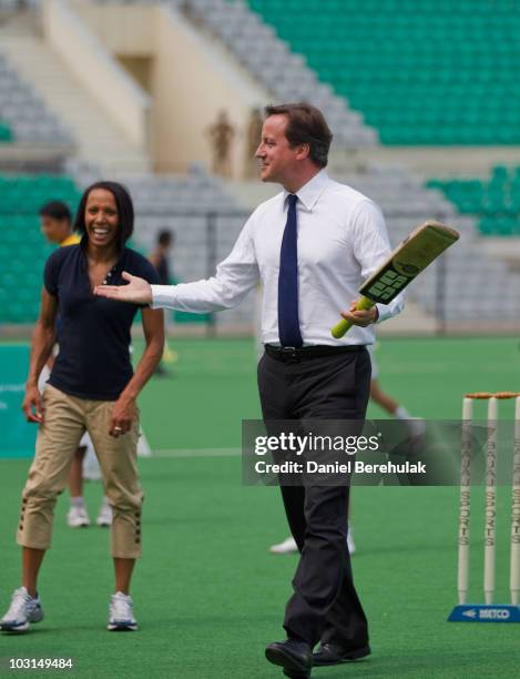 British Prime Minister David Cameron celebrates with Dame Kelly Holmes after batting against the bowling of Kapil Dev during a tour of the Dhyan...