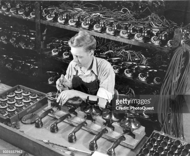 Elevated view of an unidentified Western Electric worker as he installs dials onto telephone handsets, St Louis, Missouri, 1947.